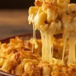 Golden baked restaurant-style mac and cheese with creamy cheddar sauce and crispy breadcrumb topping in a rustic dish, perfect for homemade comfort food
