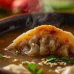 Zoomed-in shot of a steaming handmade potsticker soup with dumplings, vegetables, green onions, and sesame seeds in a rustic bowl.