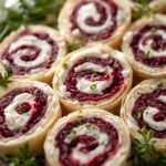 Close-up of sliced cranberry pinwheels decorated with fresh herbs on a holiday platter