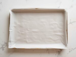 A baking sheet lined with parchment paper on a clean kitchen counter, ready for baking."