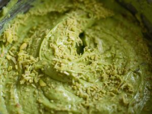 Bowl of bright green pistachio-kataifi mixture, creamy with visible crispy kataifi strands, chilled for shaping