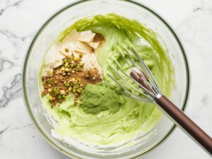 Smooth bright green pistachio cream in a bowl with melted white chocolate and butter, realistic close-up