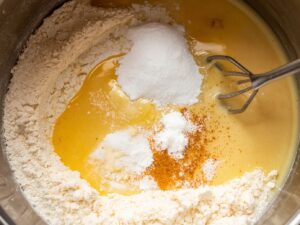 Mixing bowl with flour, cornstarch, sugar, salt, water, and oil whisked into smooth kataifi batter, close-up