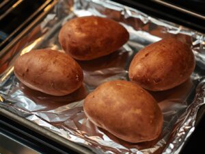 Medium sweet potatoes on a baking sheet before baking